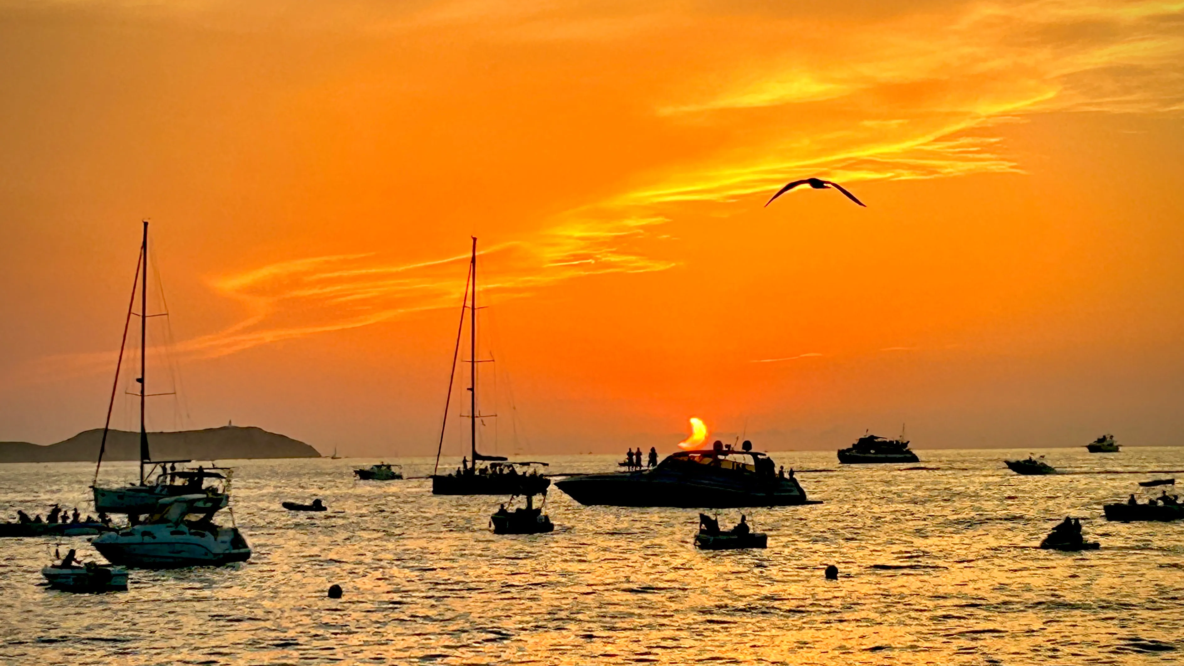 several boat are in the sea and the setting sun looks like a crescent